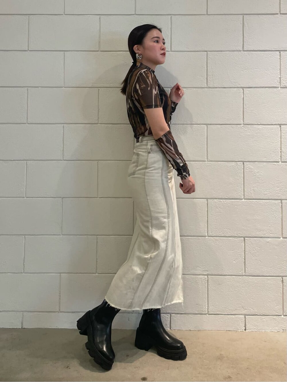 ホワイト系のスカート、ブラック系のブーツ、その他のTシャツ/カットソーを着用したレディースの夏コーディネートの2枚目の写真