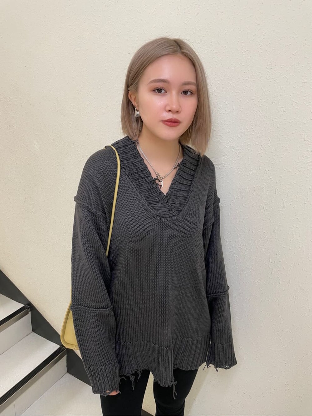 イエロー系のハンドバッグ、その他のブーツ、グレー系のニット/セーターを着用したレディースの秋コーディネートの4枚目の写真