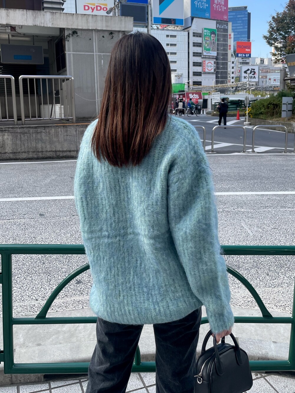 ブルー系のニット/セーター、ブラック系のデニムパンツ、ブラック系のブーツを着用したレディースの秋コーディネートの6枚目の写真