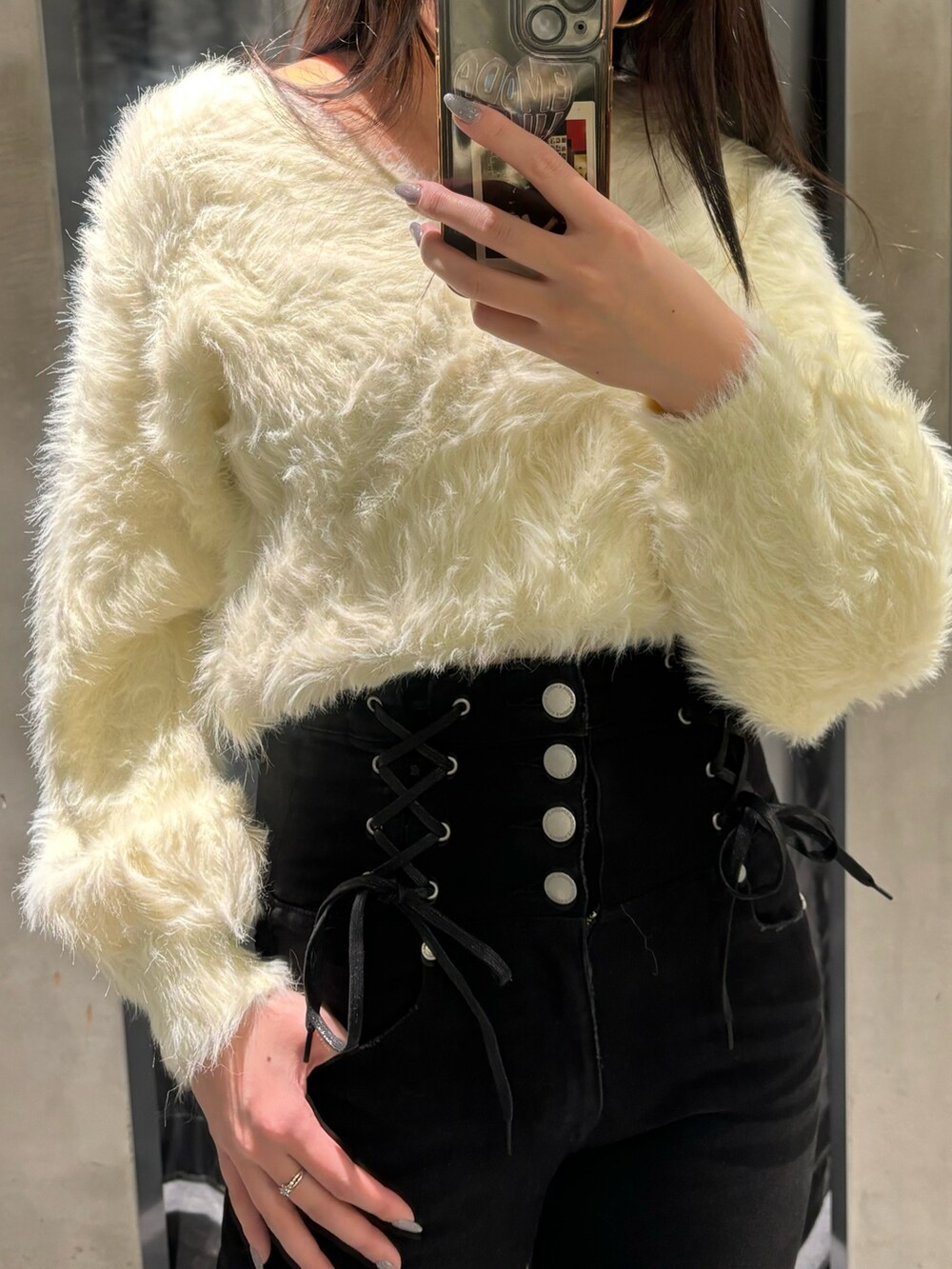 ブラック系のデニムパンツ、ホワイト系のニット/セーター、ブラック系のブーツを着用したレディースの冬コーディネートの6枚目の写真