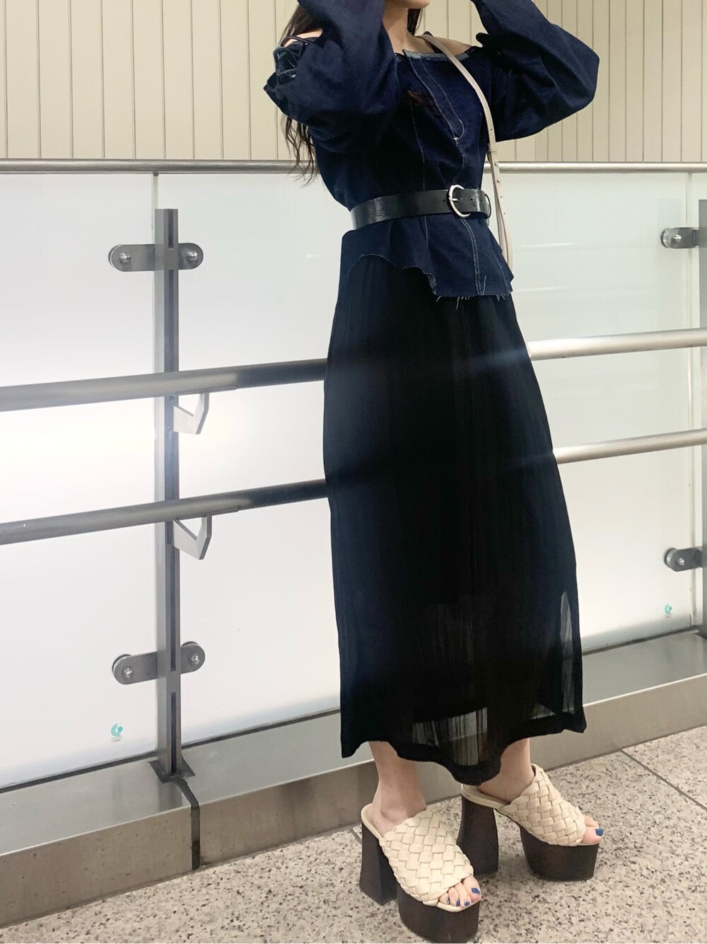 ブラック系のスカート、ホワイト系のショルダーバッグ、ホワイト系のサンダルを着用したレディースの春コーディネートの2枚目の写真