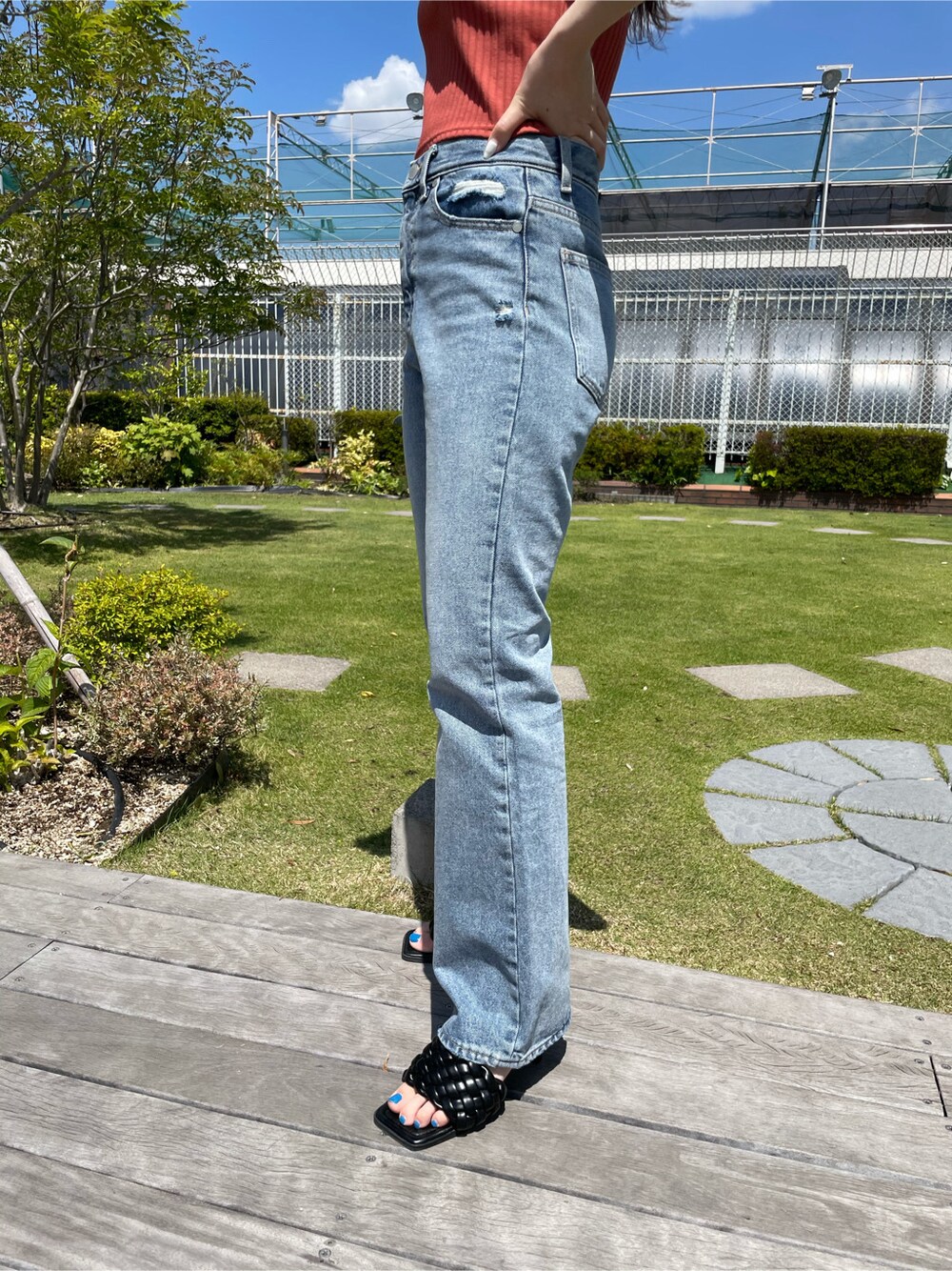 ブラック系のサンダル、ブルー系のデニムパンツ、オレンジ系のTシャツ/カットソーを着用したレディースの春コーディネートの4枚目の写真