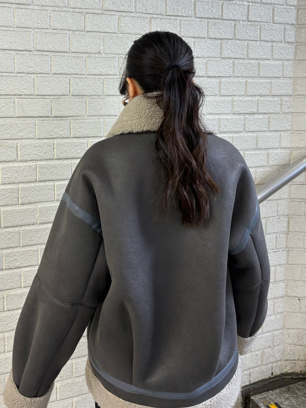 グレー系のムートンコート、ブラック系のデニムパンツ、その他のブーツを着用したレディースの秋コーディネートの6枚目の写真