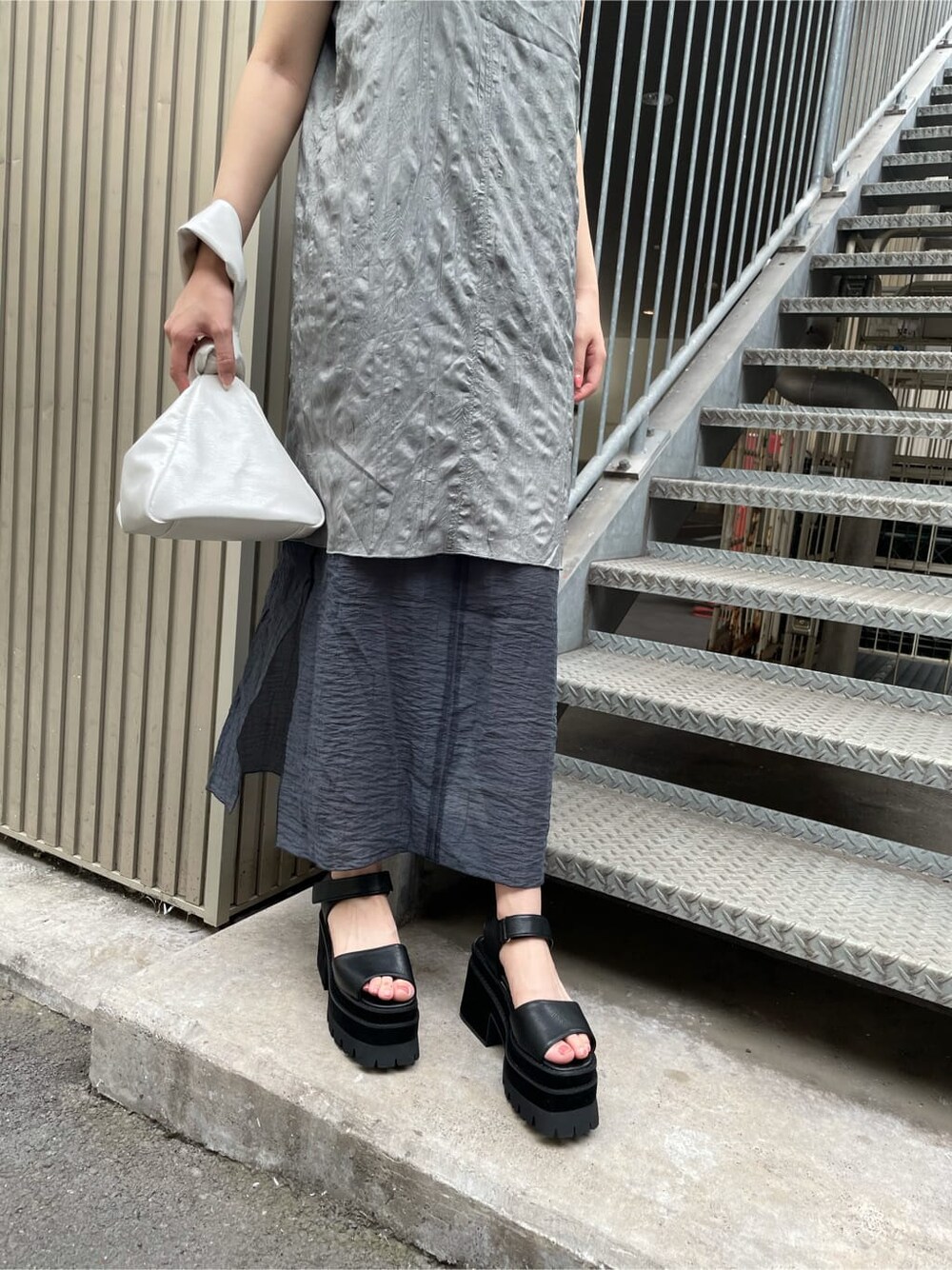 グレー系のワンピース、ホワイト系のハンドバッグを着用したレディースの夏コーディネートの3枚目の写真