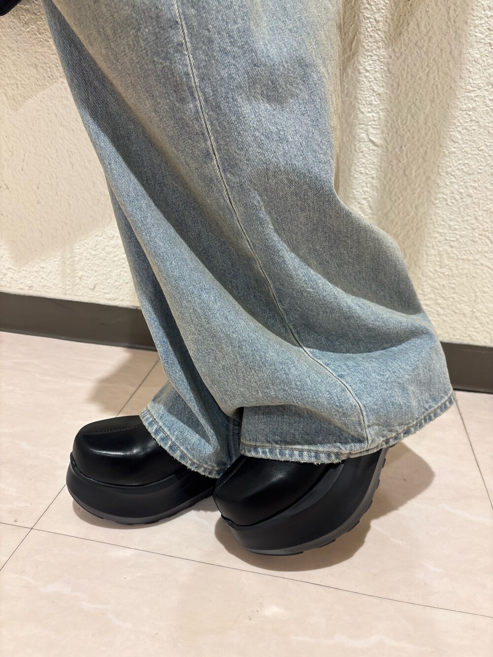 ブラック系のブーツ、ブラック系のハンドバッグ、ブルー系のデニムパンツを着用したレディースの春コーディネートの8枚目の写真