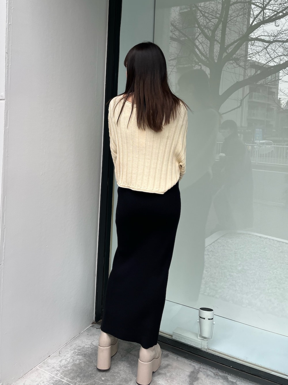 ホワイト系のニット/セーター、ベージュ系のブーツ、ブラック系のワンピースを着用したレディースの春コーディネートの3枚目の写真