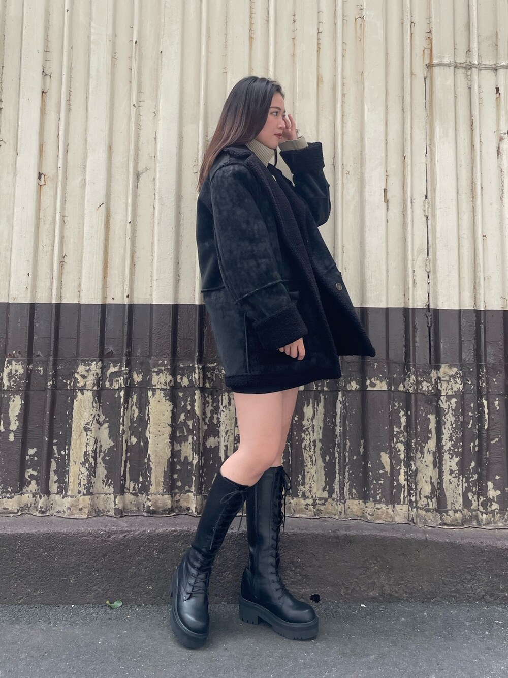 ブラック系のムートンコート、ブラック系のスカート、ホワイト系のブーツを着用したレディースの冬コーディネートの2枚目の写真