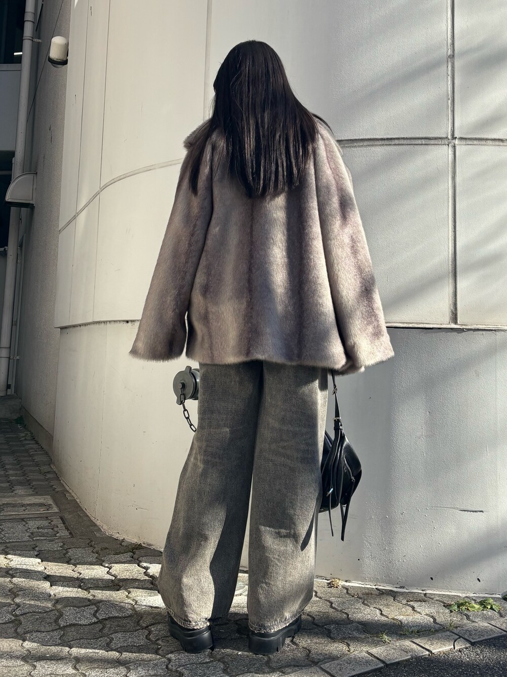 グレー系のその他アウター、ブラック系のニット/セーター、ブラック系のハンドバッグを着用したレディースの冬コーディネートの3枚目の写真