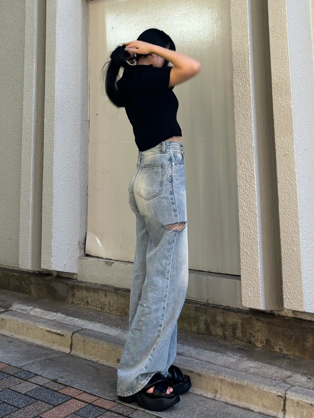 ホワイト系のデニムパンツ、ブラック系のニット/セーター、ブラック系のサンダルを着用したレディースの夏コーディネートの2枚目の写真