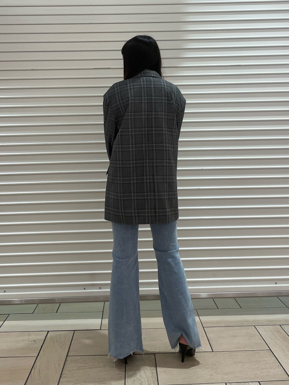 ブラック系のテーラードジャケット、ブルー系のニット/セーター、ブルー系のデニムパンツを着用したレディースの春コーディネートの3枚目の写真