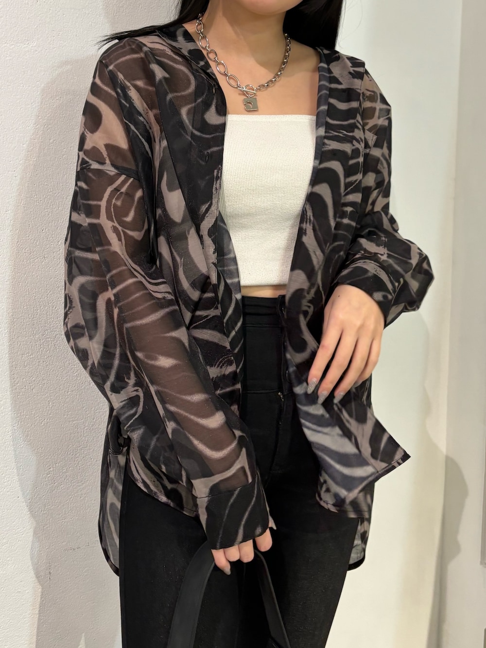 ブラック系のデニムパンツ、ベージュ系のシャツ/ブラウス、ブラック系のショルダーバッグを着用したレディースの春コーディネートの4枚目の写真