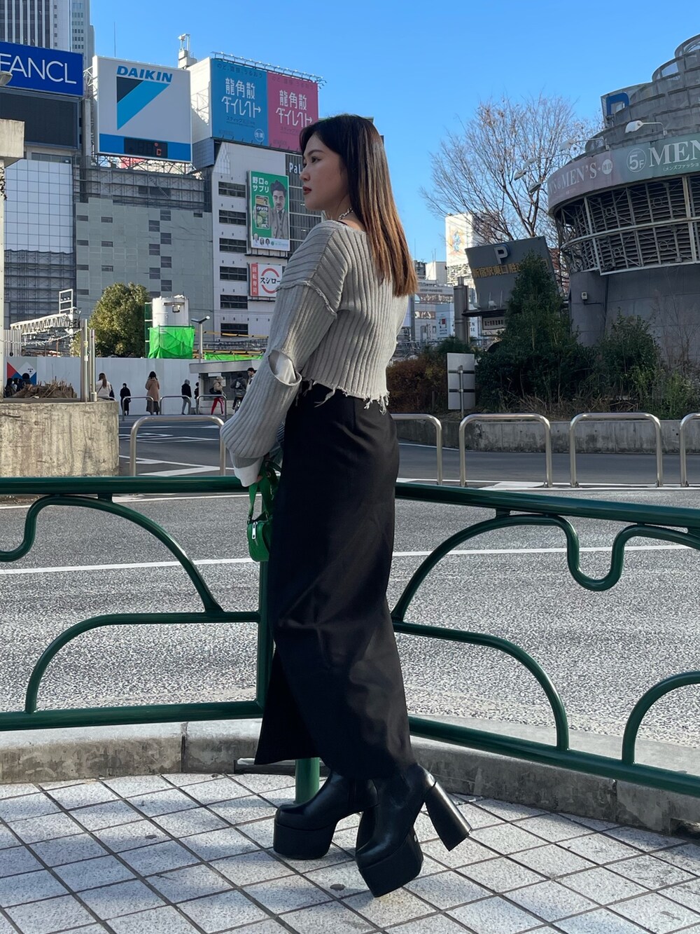 グレー系のニット/セーター、ブラック系のスカート、グリーン系のハンドバッグを着用したレディースの冬コーディネートの2枚目の写真