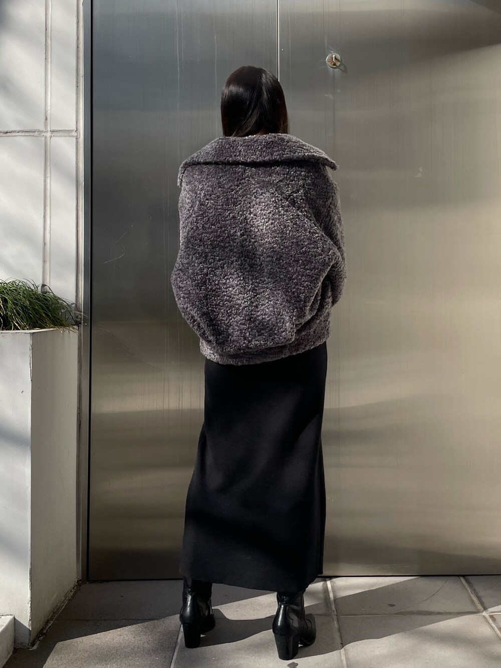 グレー系のブルゾン、ブラック系のワンピース、ブラック系のブーツを着用したレディースの冬コーディネートの3枚目の写真