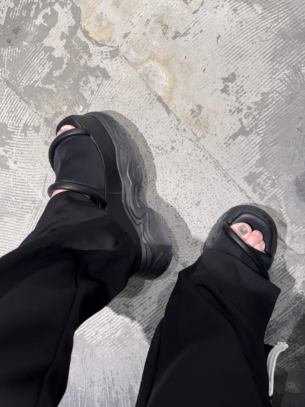 ブラック系のサンダル、ホワイト系のTシャツ/カットソー、ブラック系のスラックスを着用したレディースの夏コーディネートの7枚目の写真