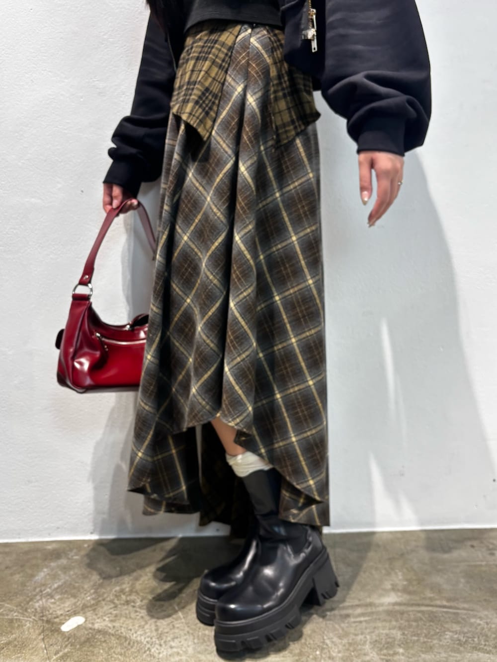 ブラウン系のブーツ、グリーン系のスカート、ブラック系のパーカーを着用したレディースの秋コーディネートの4枚目の写真