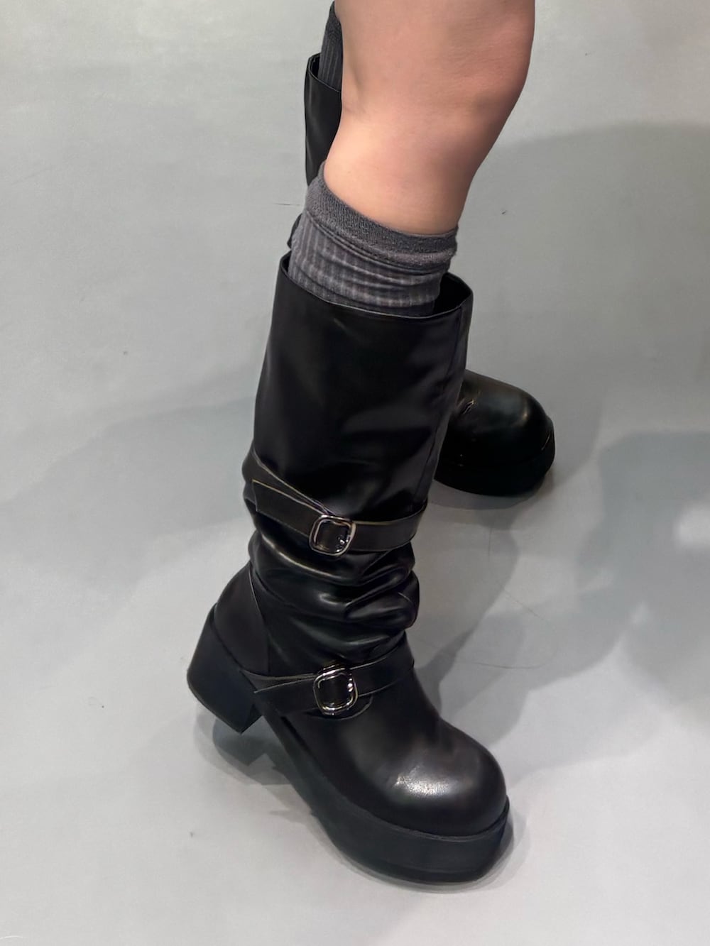 グレー系のパーカー、ブラック系のブーツ、グレー系のスカートを着用したレディースの冬コーディネートの5枚目の写真