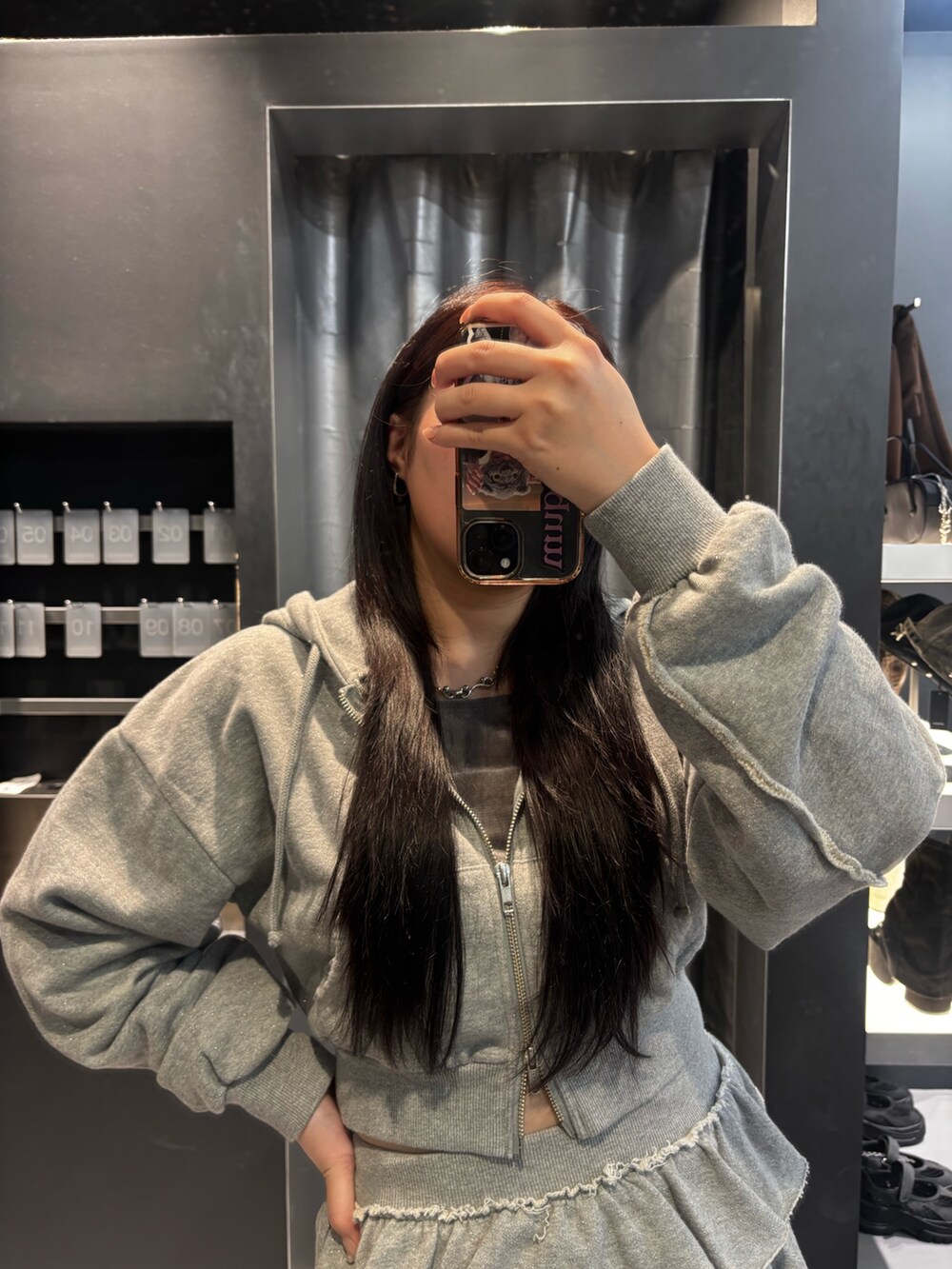 ブラック系のブーツ、ブラック系のパーカー、グレー系のスカートを着用したレディースの秋コーディネートの4枚目の写真