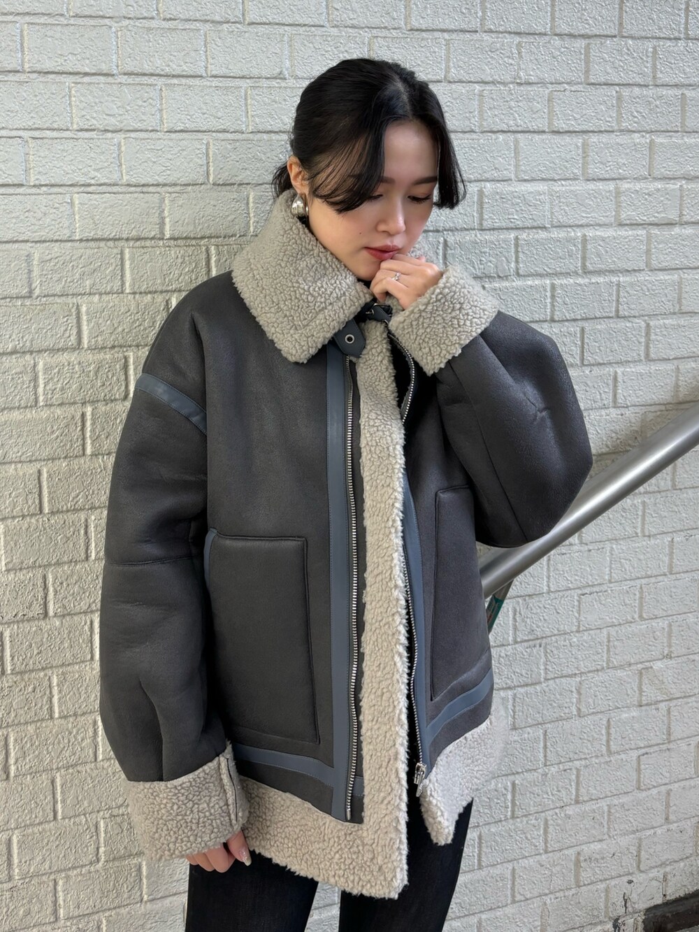 グレー系のムートンコート、ブラック系のデニムパンツ、その他のブーツを着用したレディースの秋コーディネートの4枚目の写真