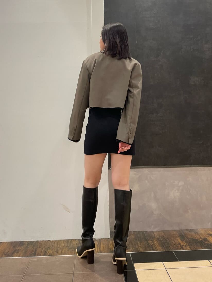 ブラック系のワンピース、ブラウン系のテーラードジャケット、ブラック系のブーツを着用したレディースの春コーディネートの2枚目の写真