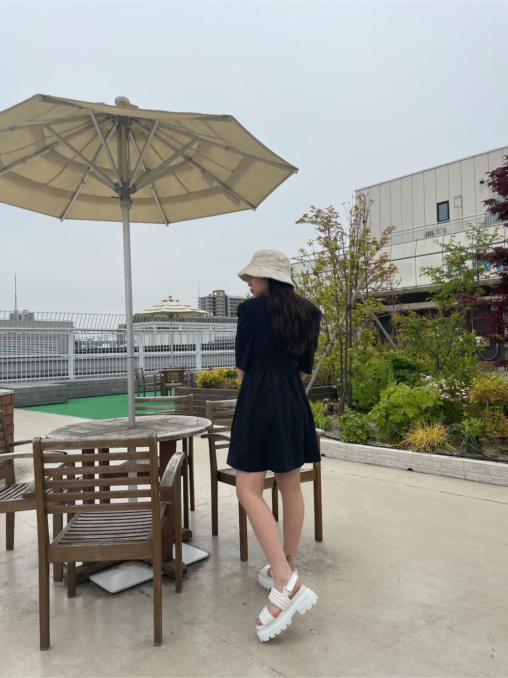 ブラック系のワンピース、ホワイト系のサンダル、ホワイト系のハットを着用したレディースの春コーディネートの2枚目の写真