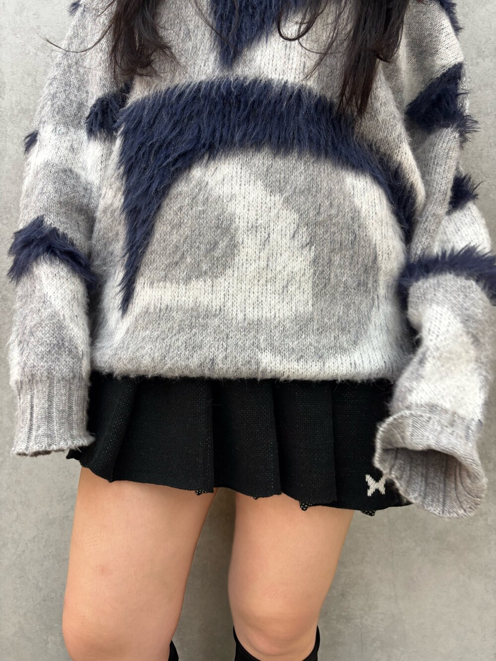 ブラック系のブーツ、ブラック系のスカート、グレー系のニット/セーターを着用したレディースの秋コーディネートの4枚目の写真