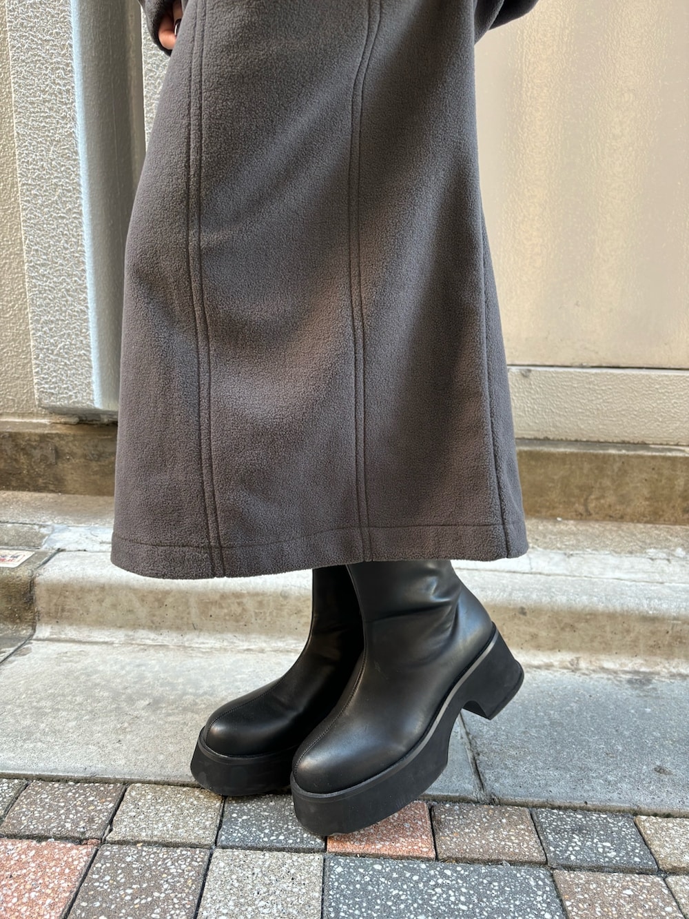 グレー系のTシャツ/カットソー、グレー系のスカート、ブラック系のブーツを着用したレディースの秋コーディネートの9枚目の写真