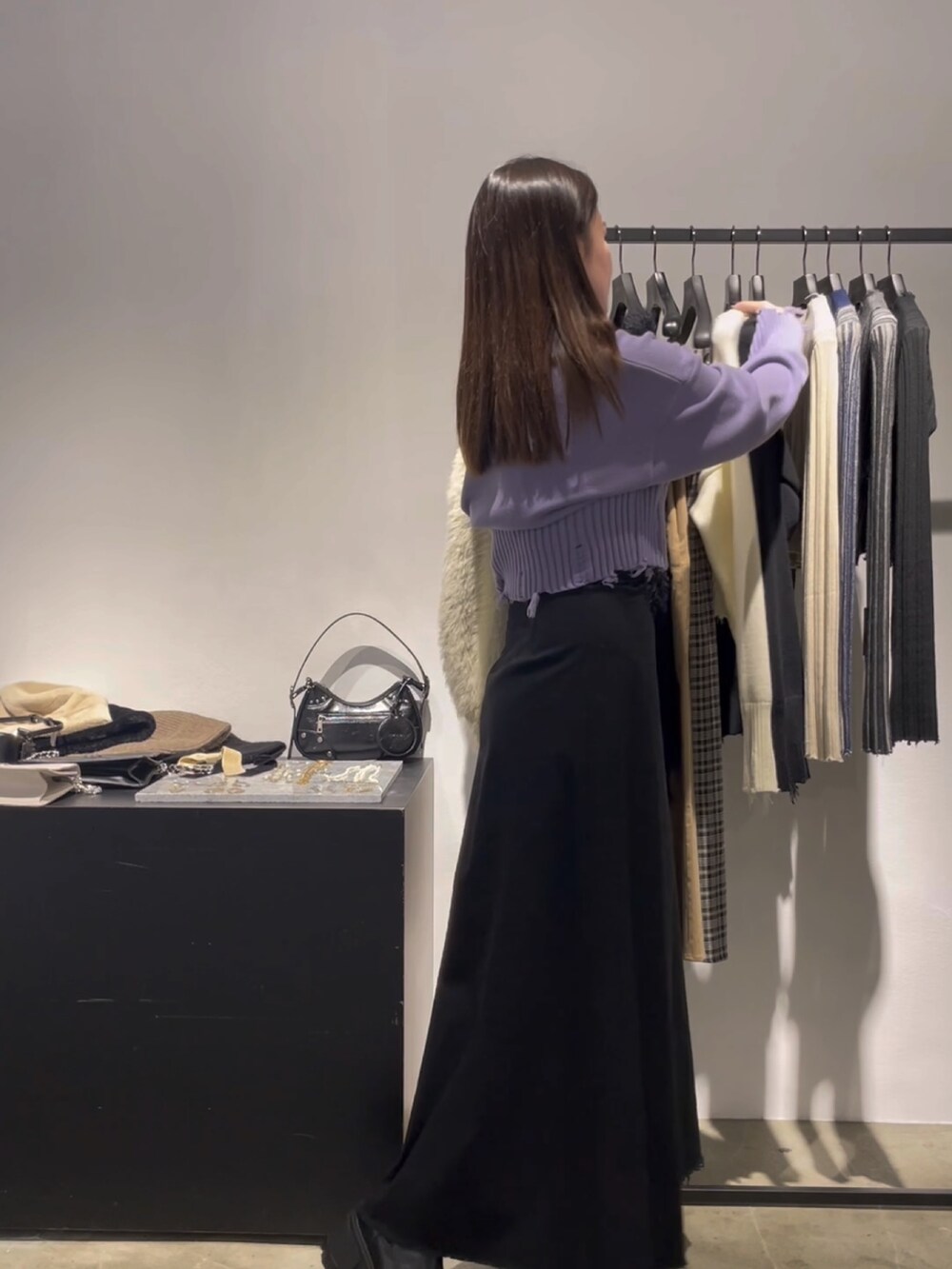 ブラック系のスカート、ブラック系のブーツ、パープル系のニット/セーターを着用したレディースの冬コーディネートの2枚目の写真