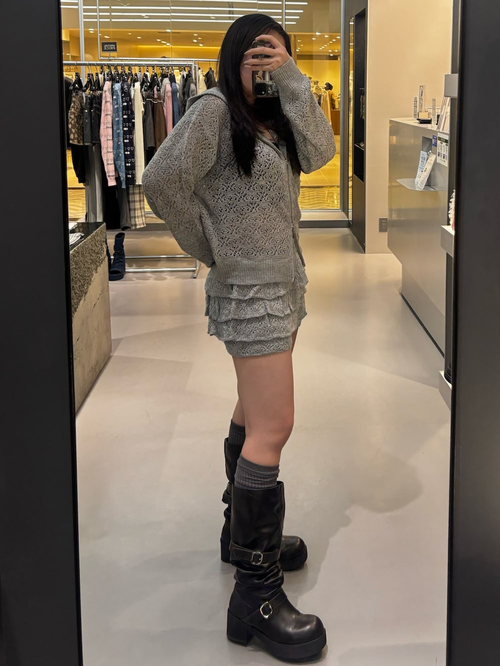 グレー系のパーカー、ブラック系のブーツ、グレー系のスカートを着用したレディースの冬コーディネートの2枚目の写真