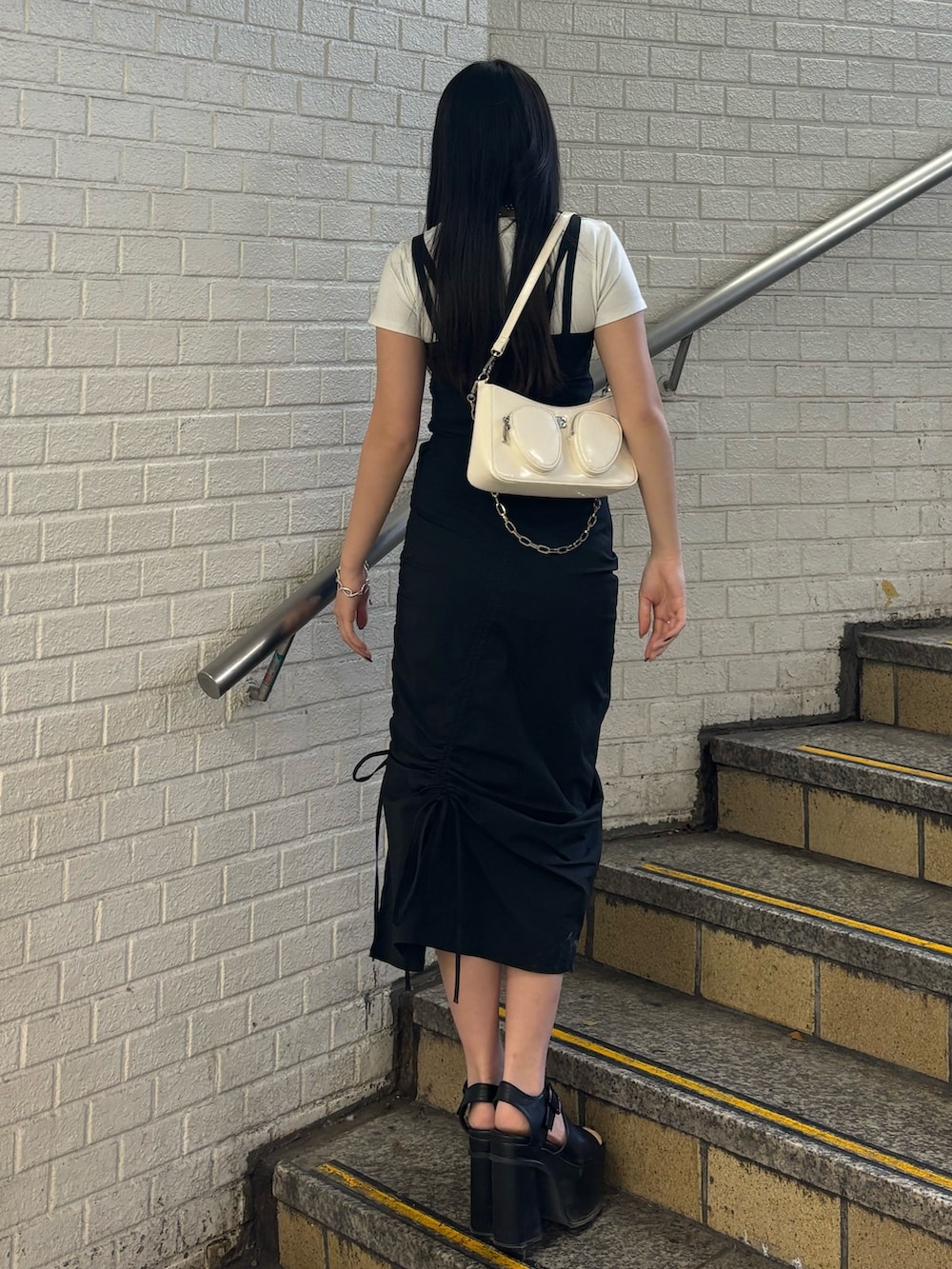 ブラック系のサンダル、ホワイト系のショルダーバッグ、ホワイト系のTシャツ/カットソーを着用したレディースの春コーディネートの3枚目の写真