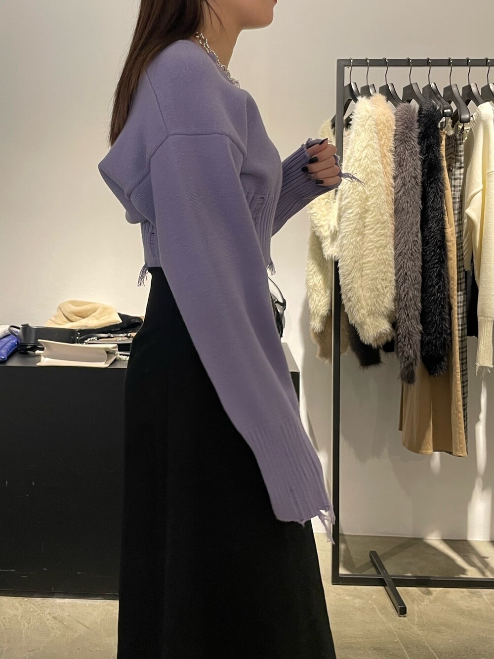 ブラック系のスカート、ブラック系のブーツ、パープル系のニット/セーターを着用したレディースの冬コーディネートの4枚目の写真