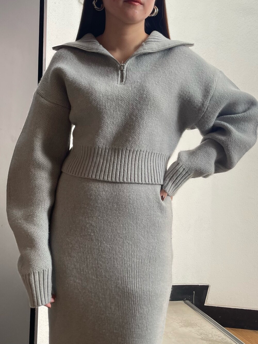 グレー系のニット/セーター、グレー系のスカート、ブラック系のブーツを着用したレディースの冬コーディネートの4枚目の写真