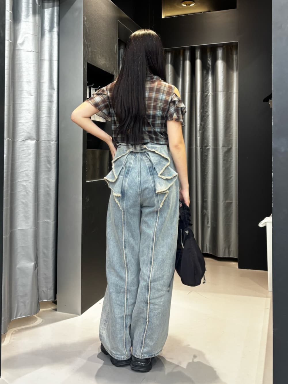 ブラック系のスニーカー、ブルー系のデニムパンツ、ブラック系のショルダーバッグを着用したレディースの夏コーディネートの2枚目の写真