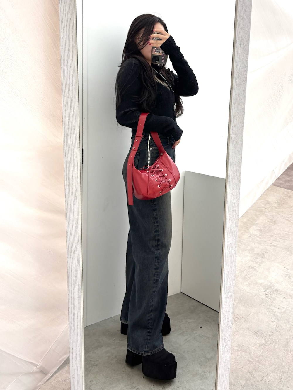 ブラック系のブーツ、ブルー系のデニムパンツ、レッド系のショルダーバッグを着用したレディースの秋コーディネートの2枚目の写真