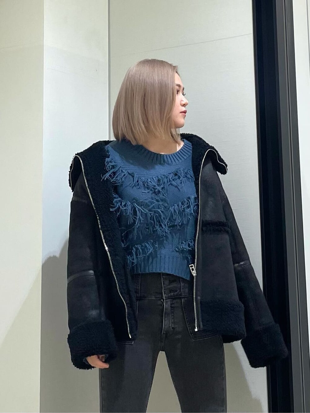 ブラック系のブーツ、グレー系のデニムパンツ、ブラック系のムートンコートを着用したレディースの冬コーディネートの4枚目の写真