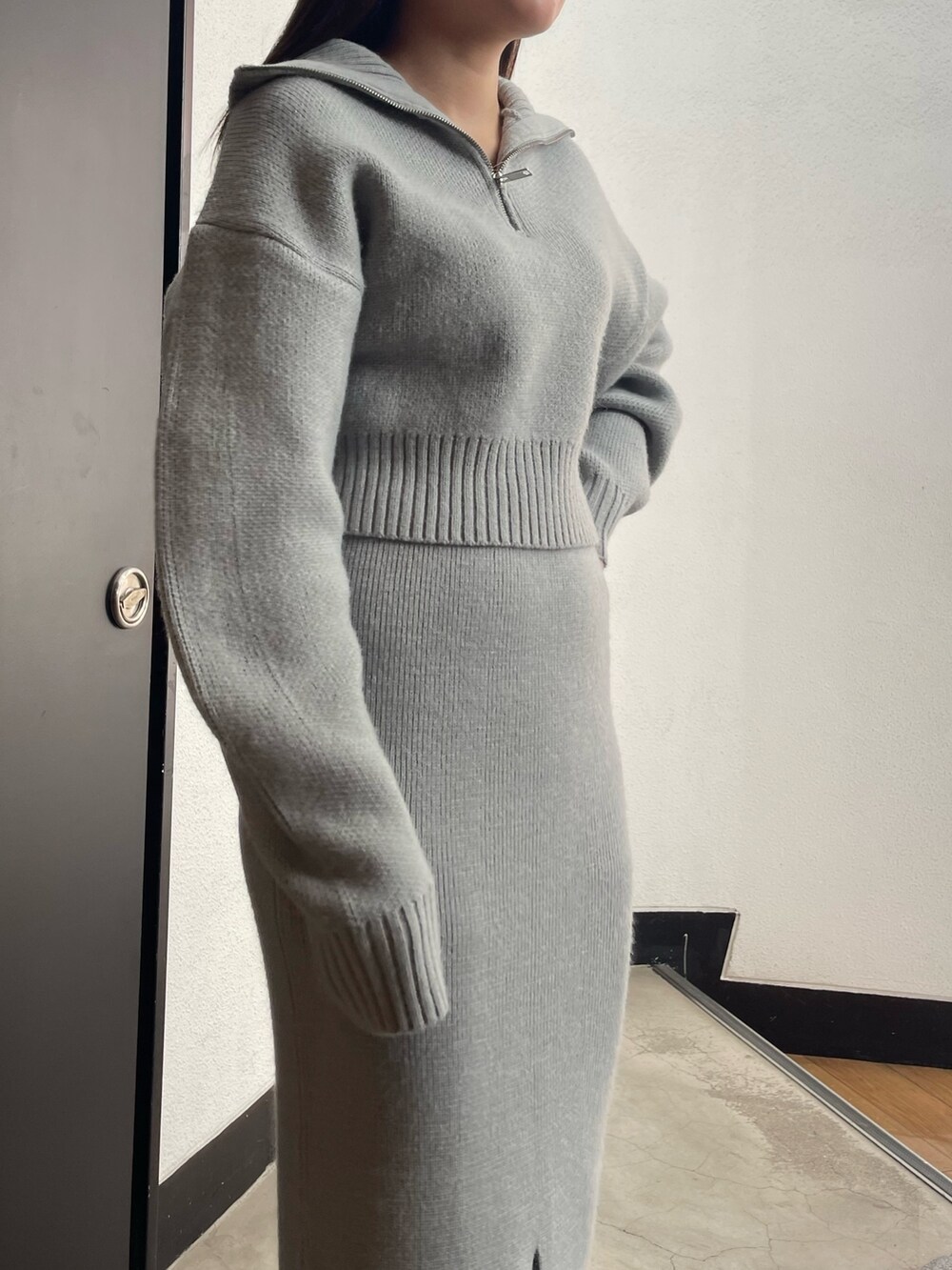 グレー系のニット/セーター、グレー系のスカート、ブラック系のブーツを着用したレディースの冬コーディネートの5枚目の写真