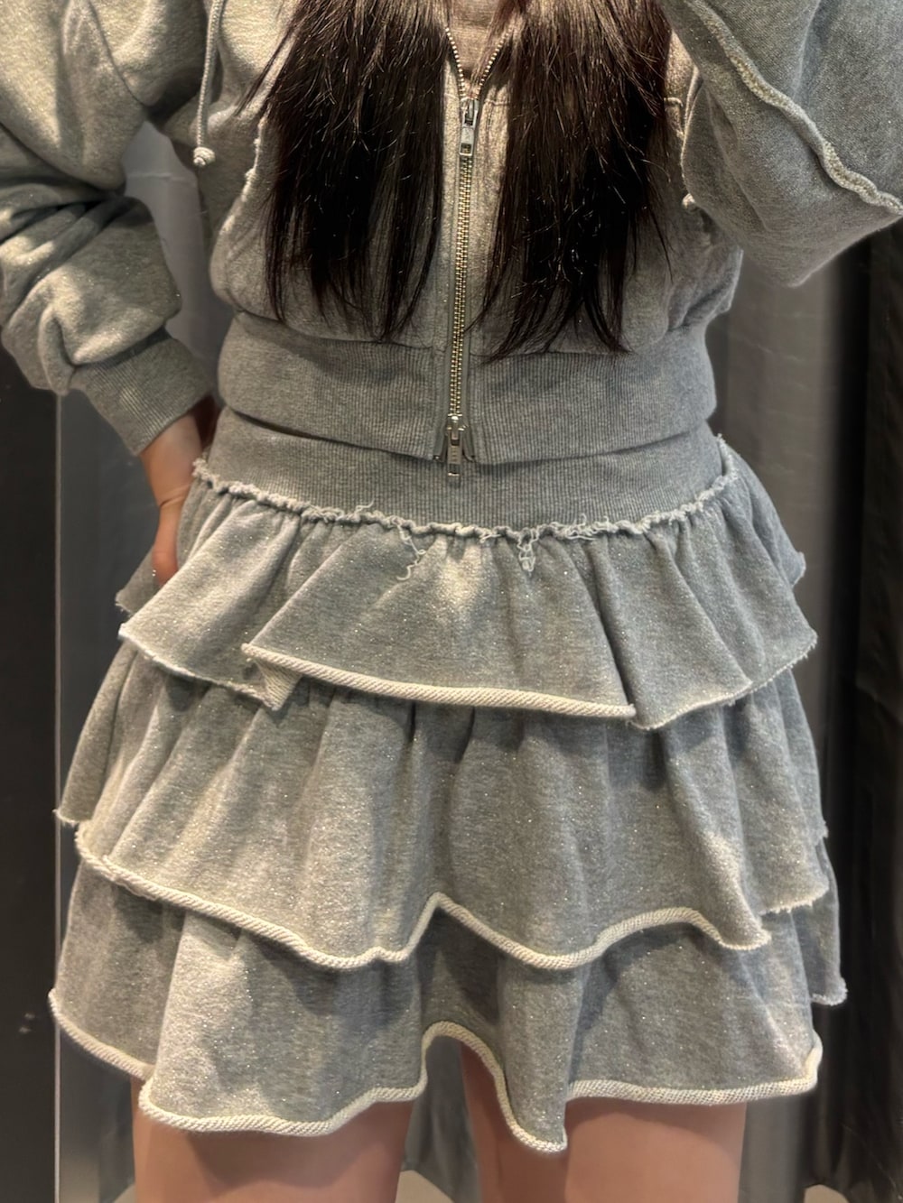 ブラック系のブーツ、ブラック系のパーカー、グレー系のスカートを着用したレディースの秋コーディネートの5枚目の写真