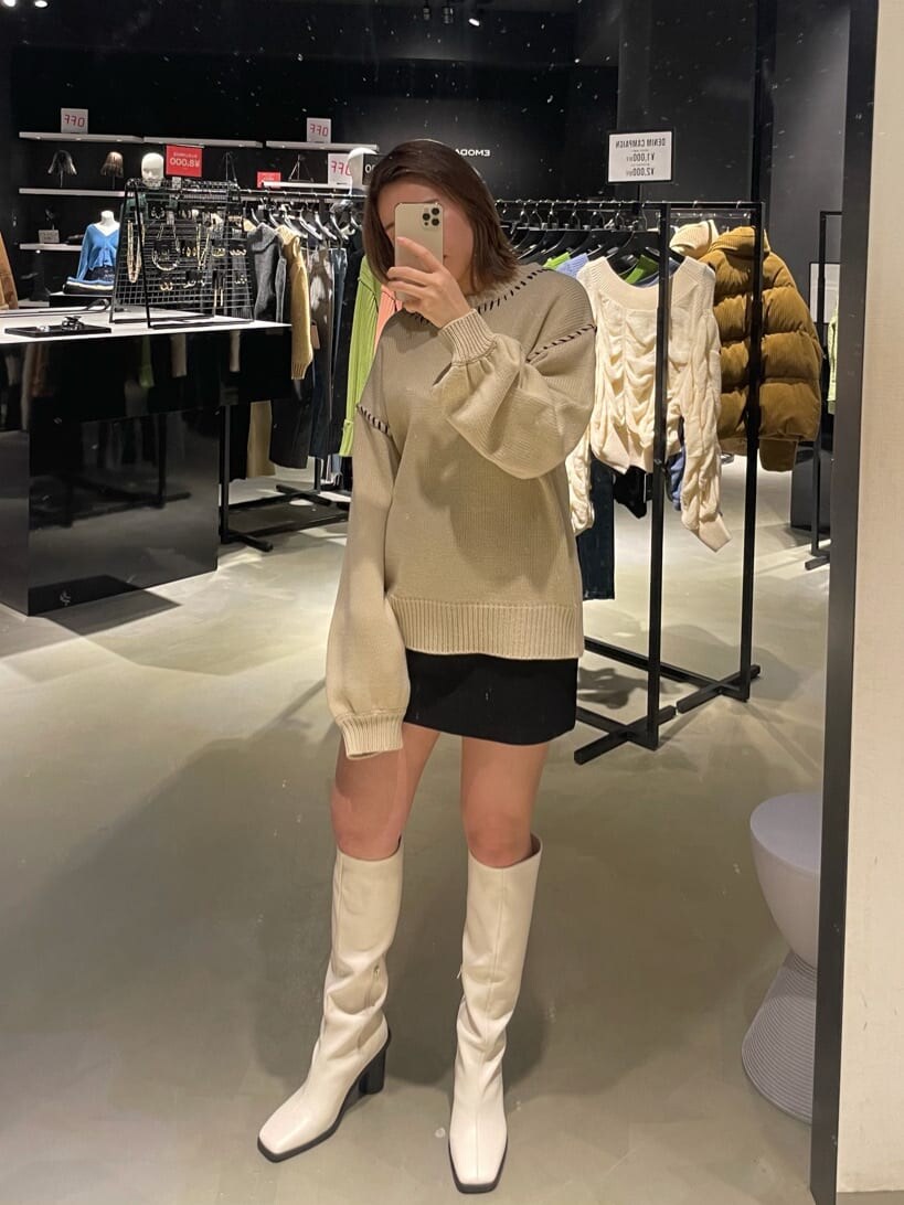 ブラック系のブルゾン、ホワイト系のブーツ、ホワイト系のニット/セーターを着用したレディースの冬コーディネートの2枚目の写真