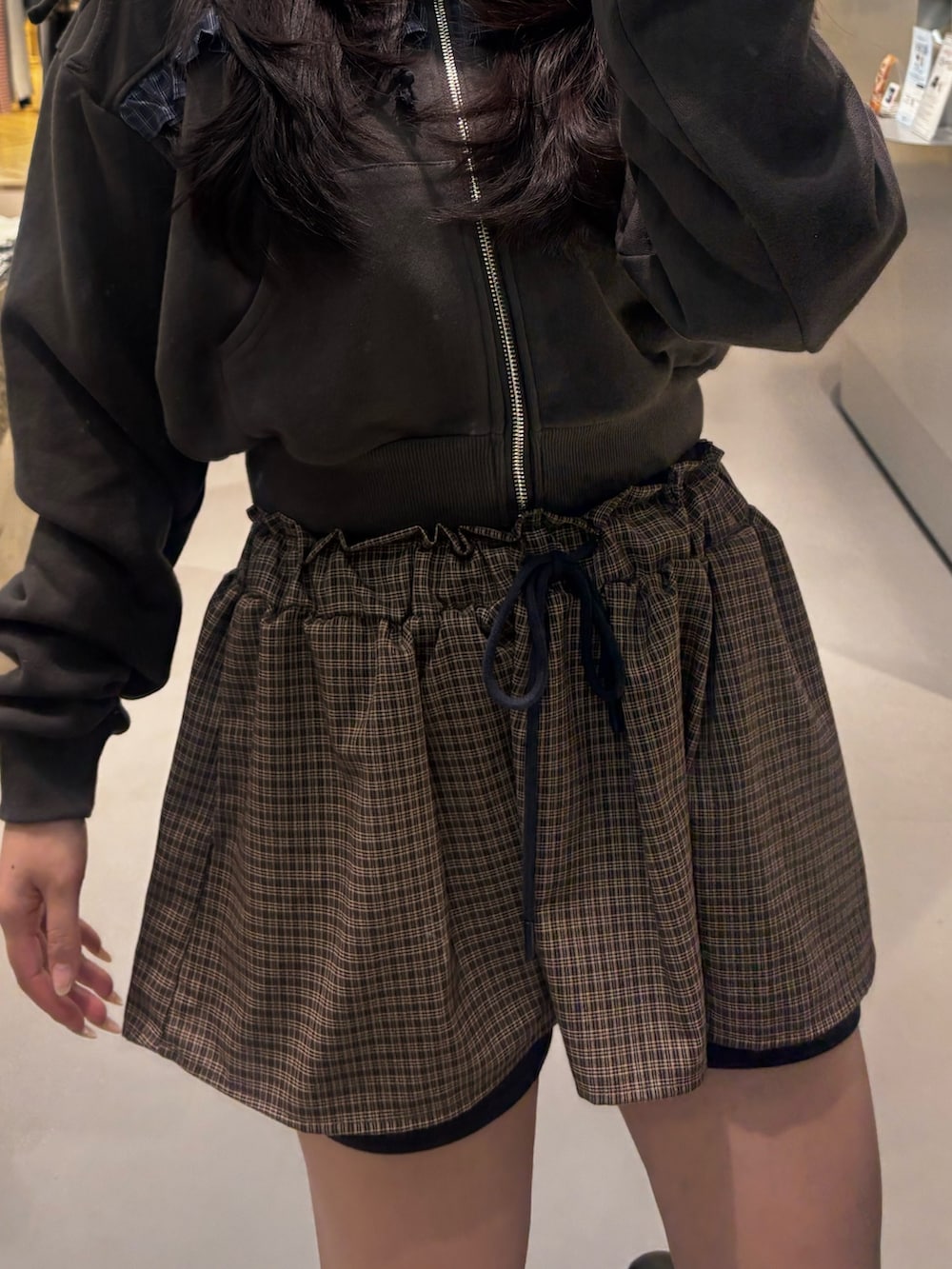 ブラック系のブーツ、ブラック系のスカート、ブラック系のパーカーを着用したレディースの冬コーディネートの4枚目の写真