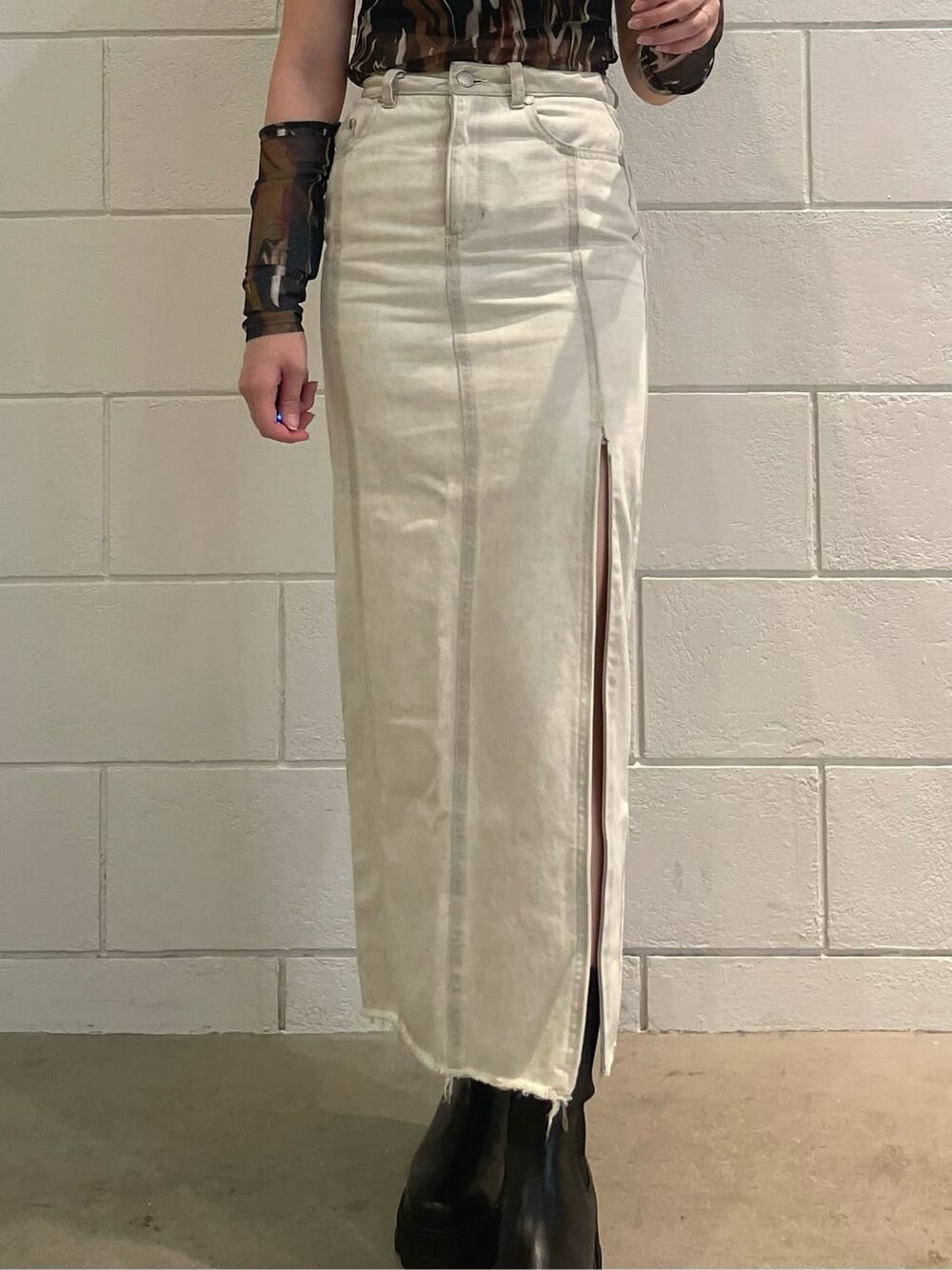 ホワイト系のスカート、ブラック系のブーツ、その他のTシャツ/カットソーを着用したレディースの夏コーディネートの5枚目の写真