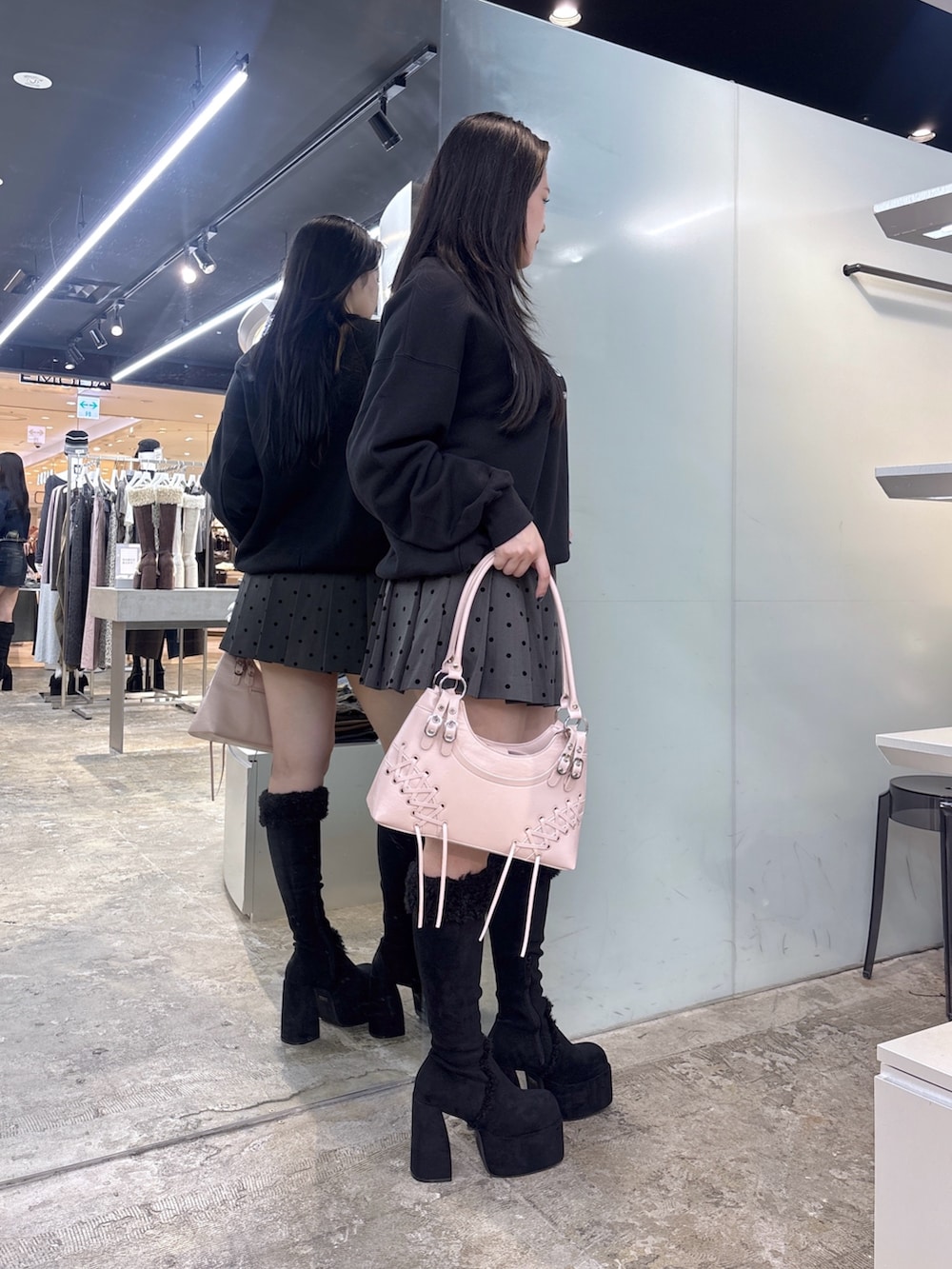 ブラック系のブーツ、グレー系のスカート、ブラック系のショルダーバッグを着用したレディースの秋コーディネートの3枚目の写真