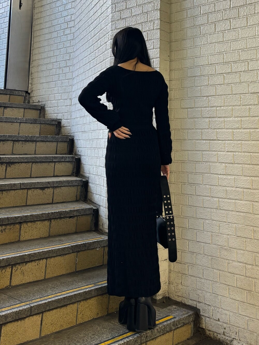 ブラック系のニット/セーター、ブラック系のスカート、ブラック系のショルダーバッグを着用したレディースの冬コーディネートの3枚目の写真