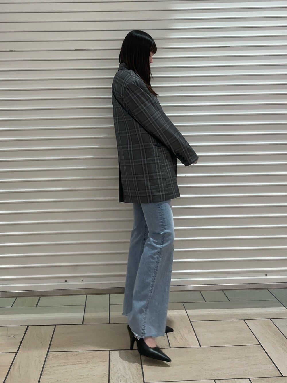 ブラック系のテーラードジャケット、ブルー系のニット/セーター、ブルー系のデニムパンツを着用したレディースの春コーディネートの2枚目の写真