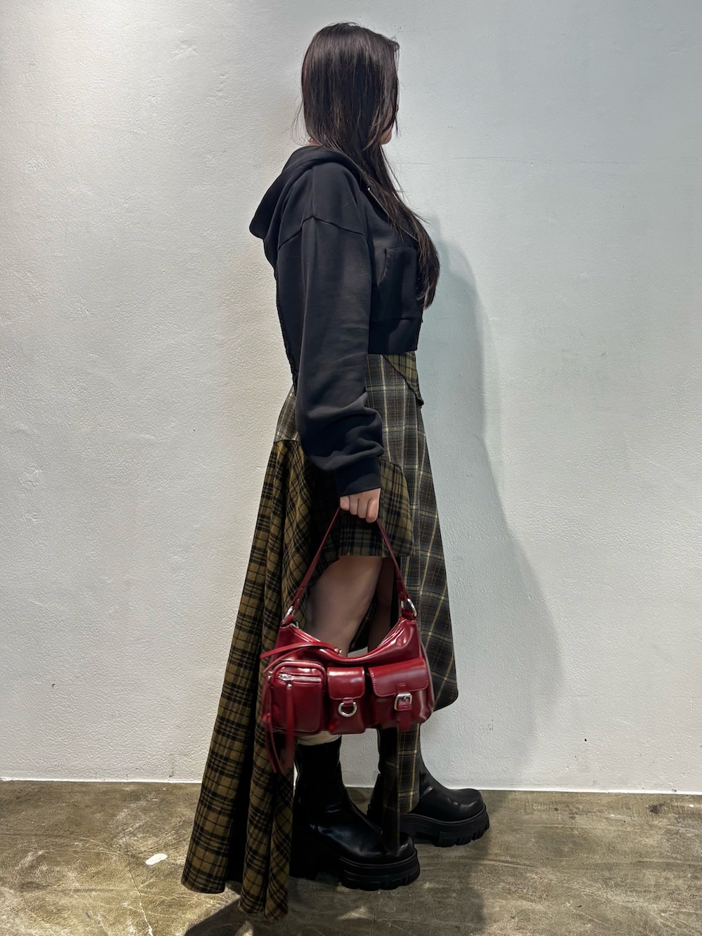 ブラウン系のブーツ、グリーン系のスカート、ブラック系のパーカーを着用したレディースの秋コーディネートの2枚目の写真