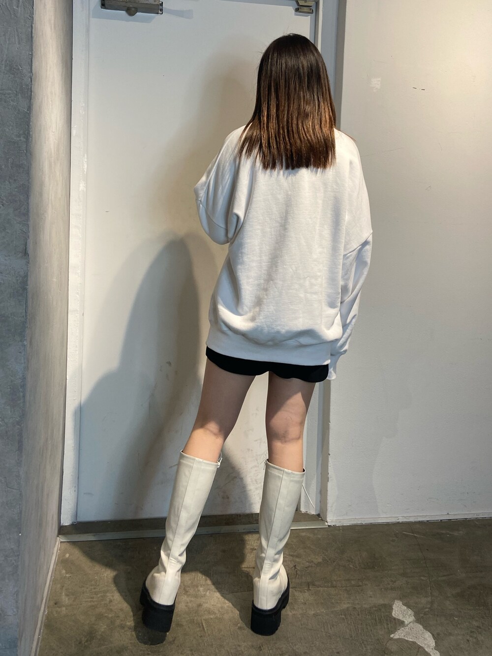 ホワイト系のスウェット、ホワイト系のブーツ、ブラック系のスカートを着用したレディースの冬コーディネートの3枚目の写真