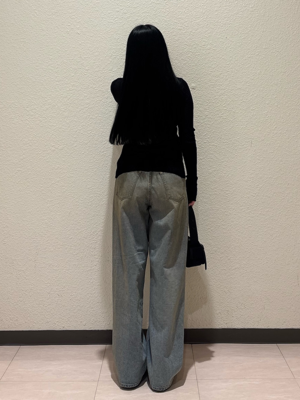 ブラック系のブーツ、ブラック系のハンドバッグ、ブルー系のデニムパンツを着用したレディースの春コーディネートの3枚目の写真