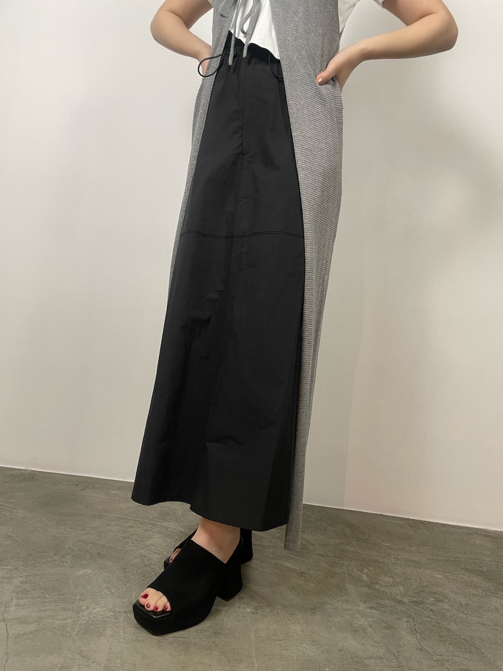 ブラック系のスカート、ホワイト系のTシャツ/カットソー、ブラック系のサンダルを着用したレディースの夏コーディネートの7枚目の写真