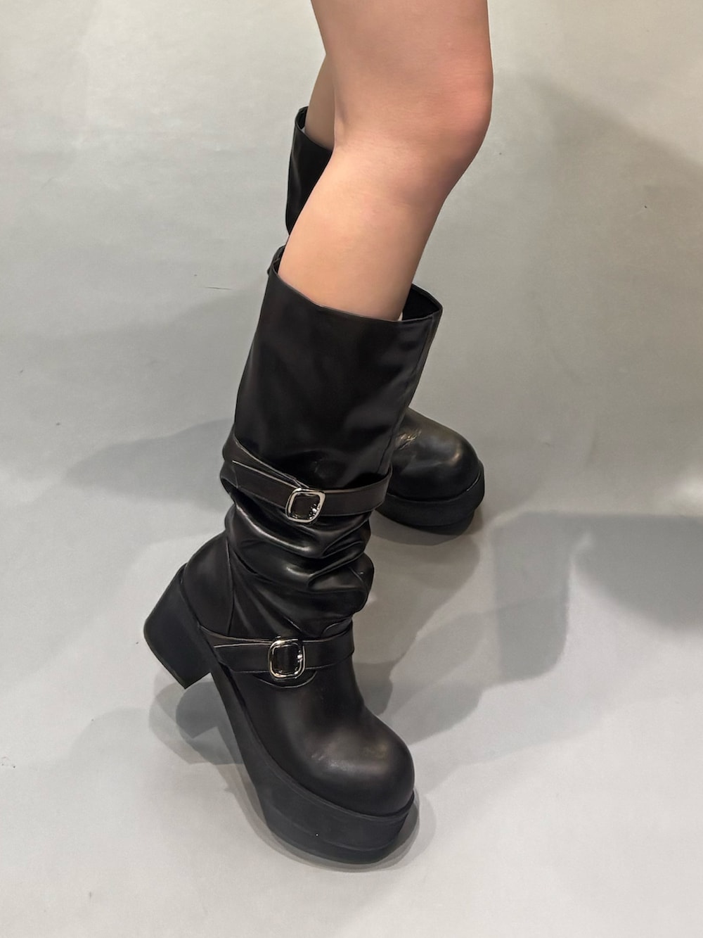 ブラック系のブーツ、ブラック系のパーカー、ブルー系のスカートを着用したレディースの冬コーディネートの5枚目の写真