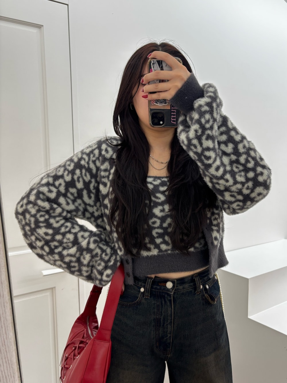 ブラック系のブーツ、ブルー系のデニムパンツ、レッド系のショルダーバッグを着用したレディースの秋コーディネートの4枚目の写真