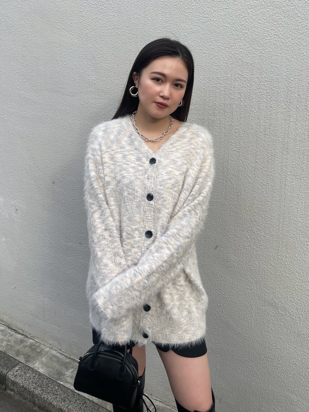 ブラック系のチェスターコート、その他のカーディガン/ボレロ、ブラック系のブーツを着用したレディースの冬コーディネートの6枚目の写真