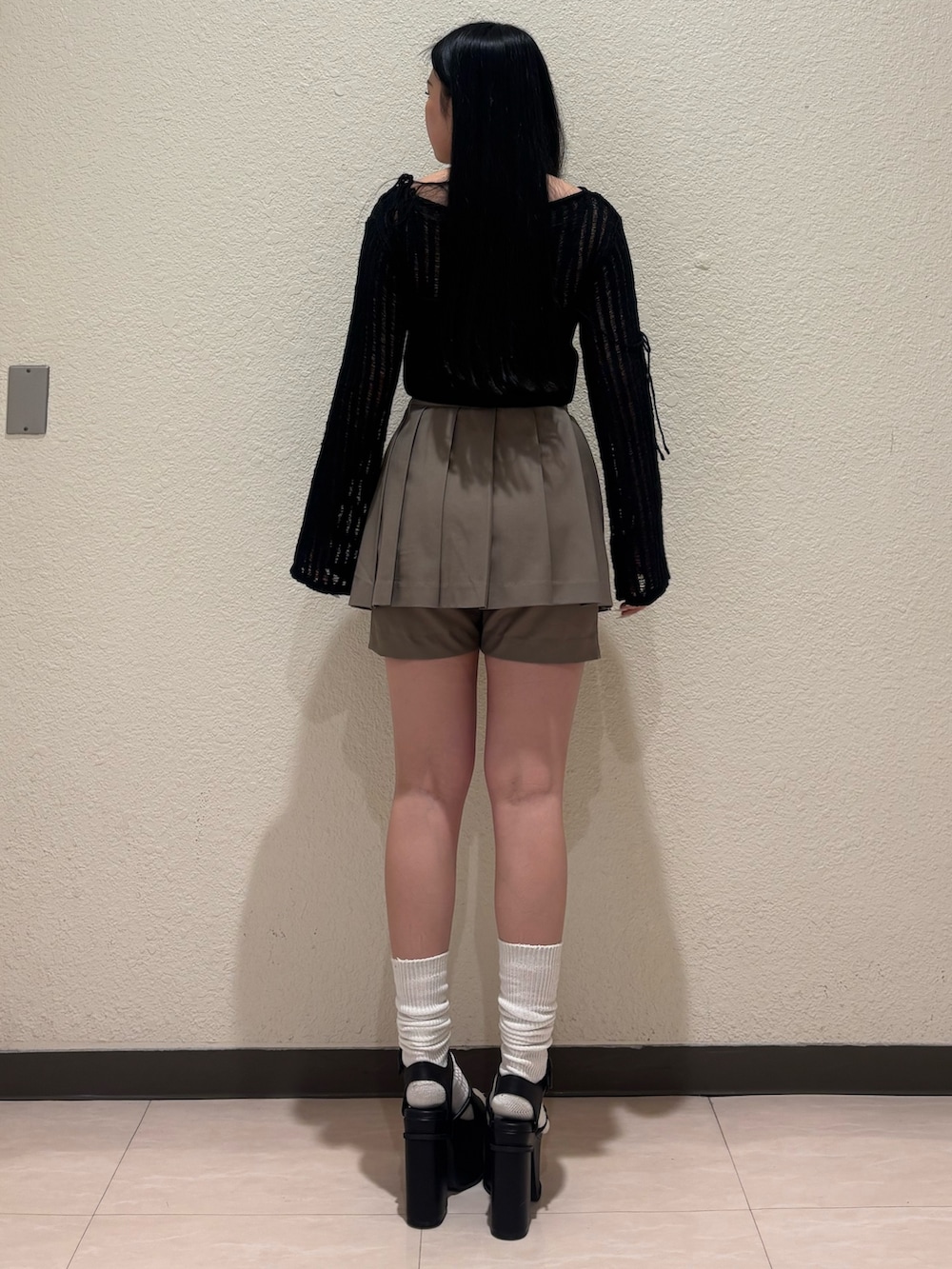 ブラック系のサンダル、ベージュ系のスカート、ブラック系のニット/セーターを着用したレディースの春コーディネートの3枚目の写真